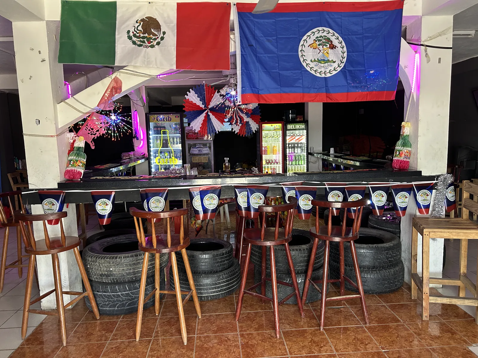 Bar seating made from repurposed tires, with Belize and Mexico flags above the counter