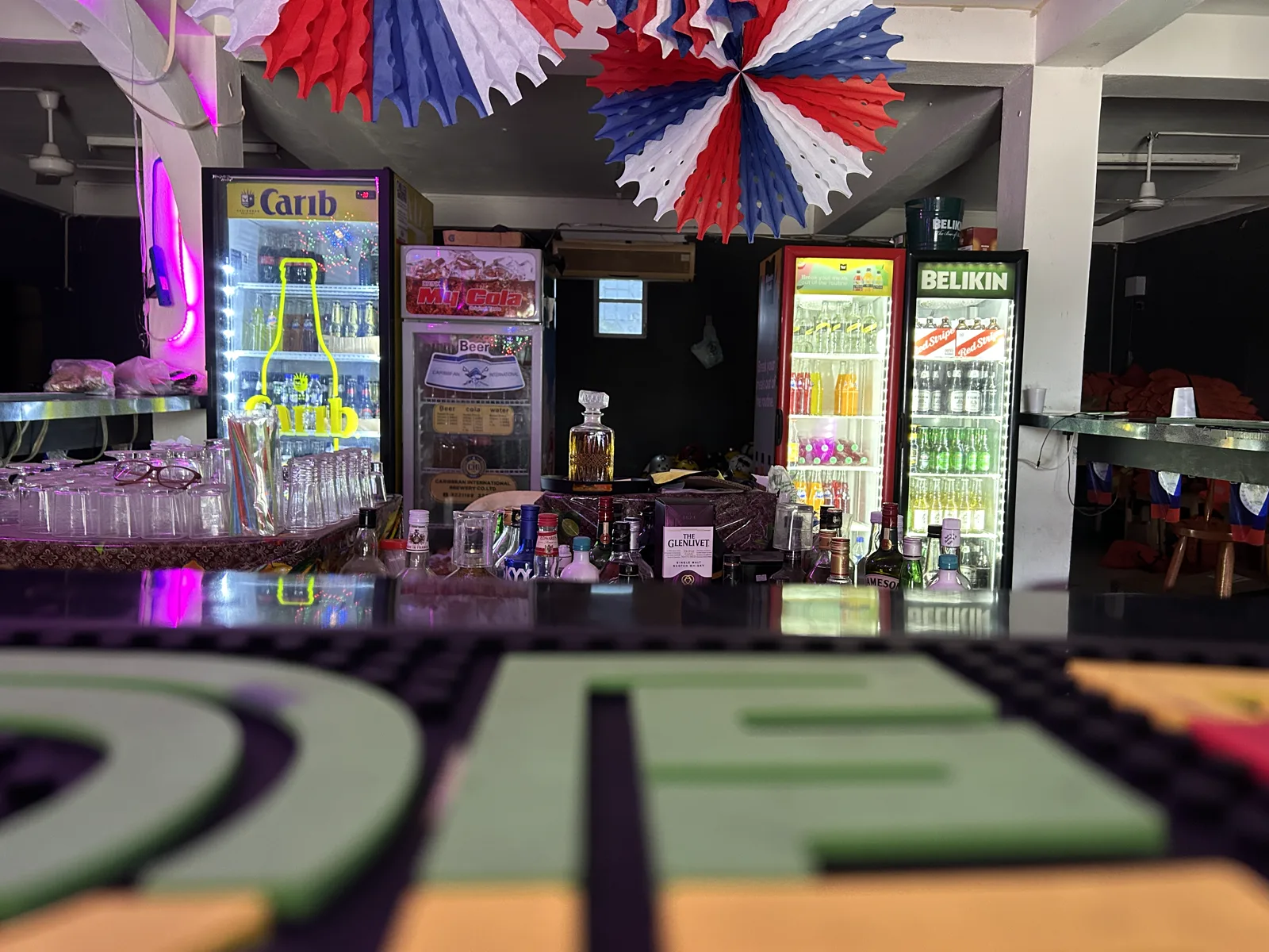 Bar counter stocked with liquor bottles and drink fridges